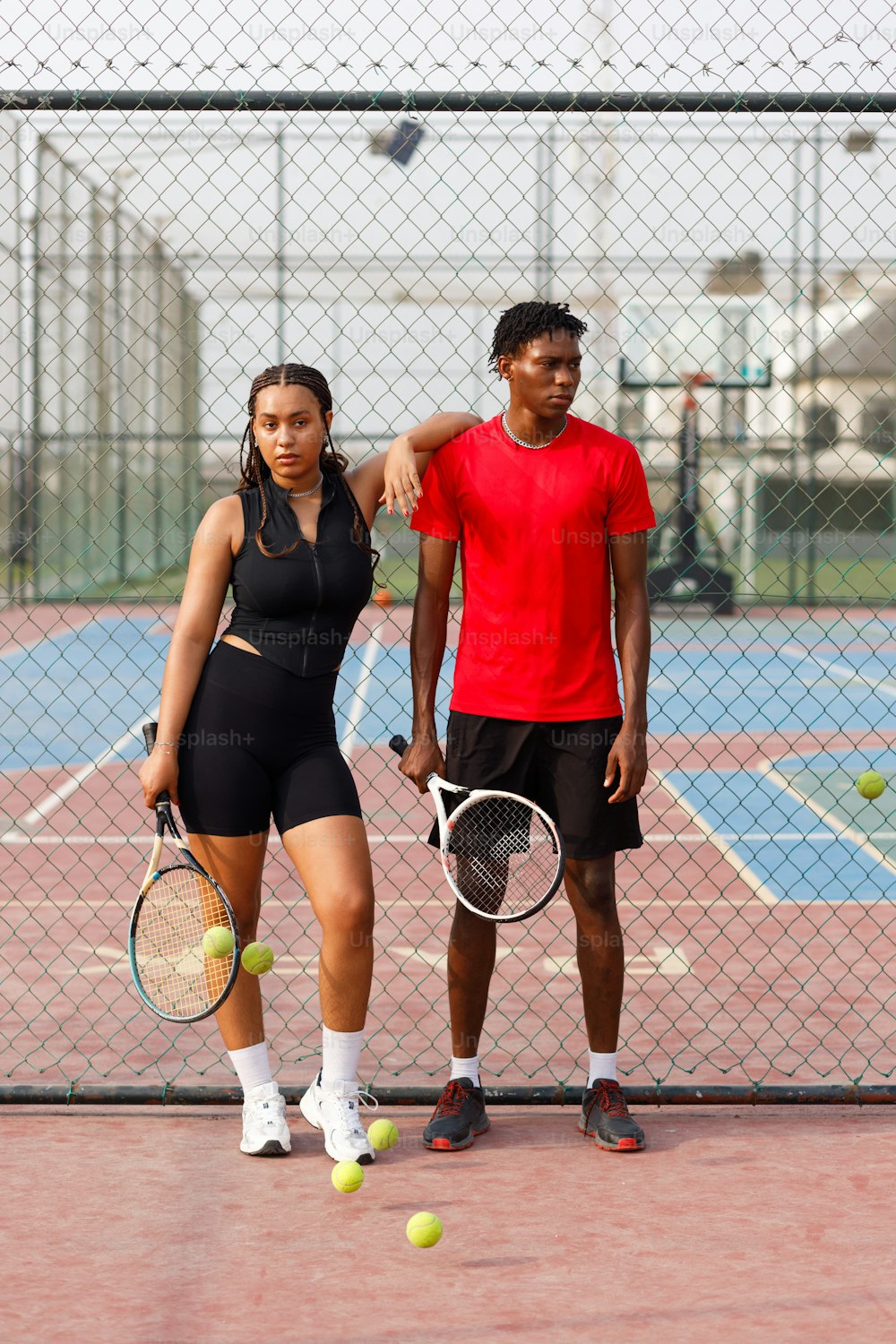 テニスコートに立ってラケットを手にし�た男女