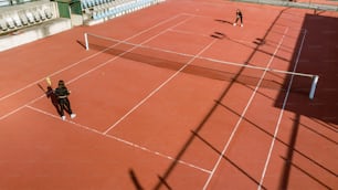 Un par de personas de pie en una cancha de tenis sosteniendo raquetas