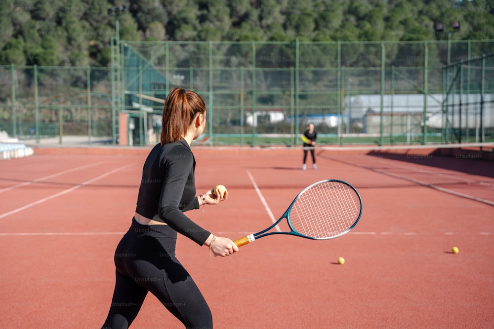 una mujer sosteniendo una raqueta de tenis encima de una cancha de tenis