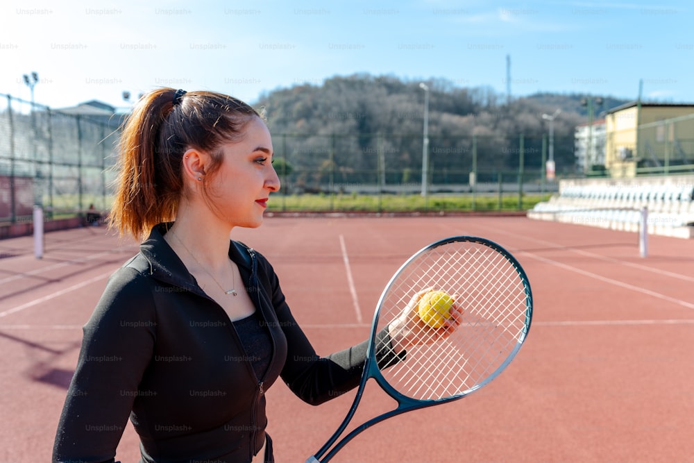 una donna che tiene una racchetta da tennis e una pallina da tennis