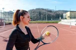 uma mulher segurando uma raquete de tênis e uma bola de tênis