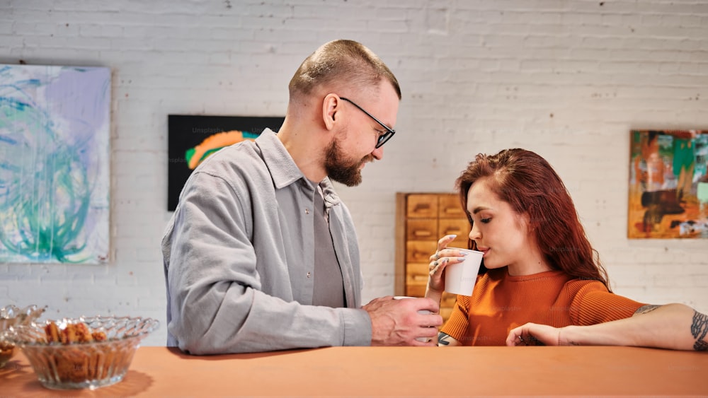un uomo in piedi accanto a una donna che tiene una tazza