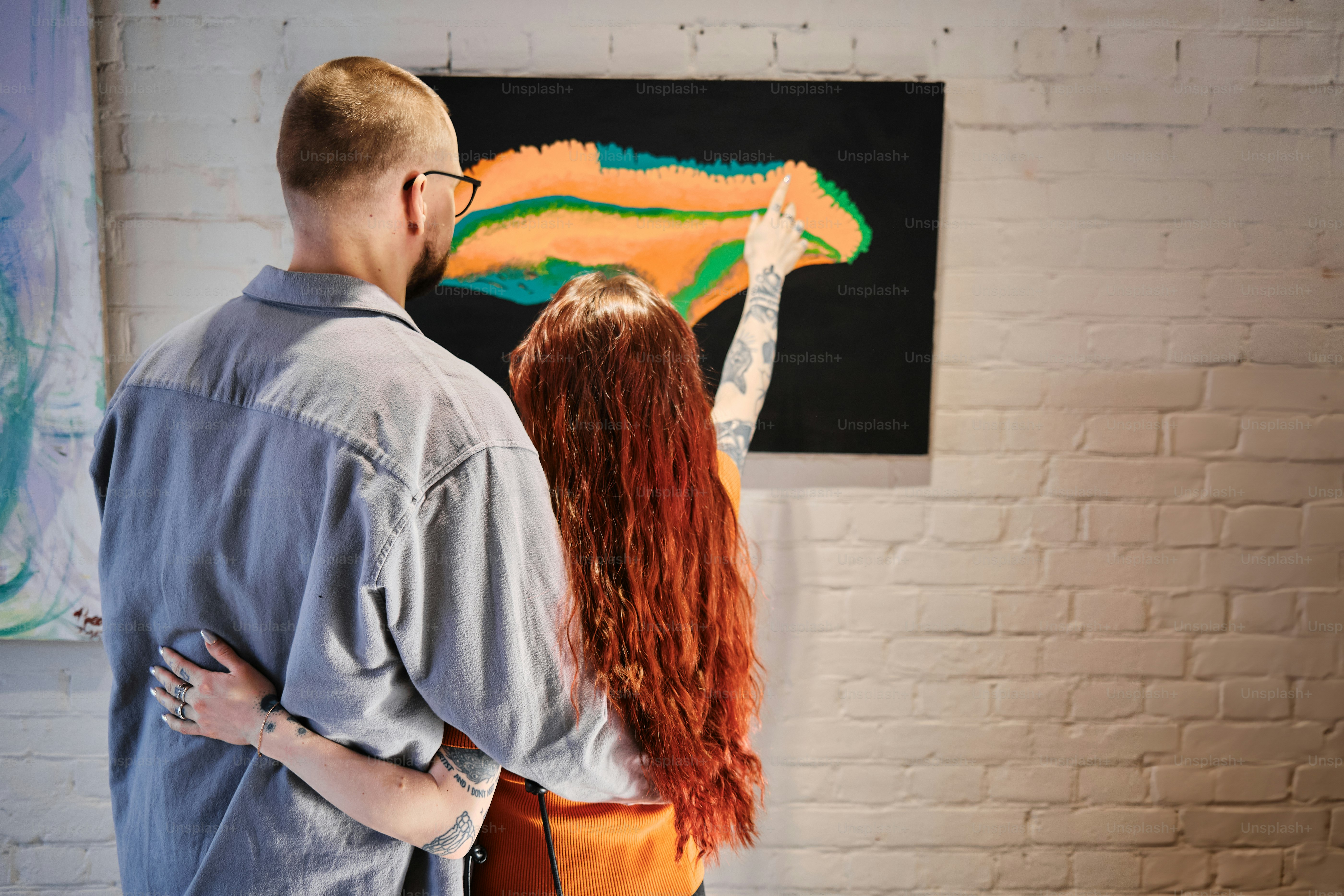 a man and a woman standing in front of a painting