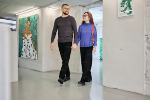 a man and a woman are walking through an art gallery