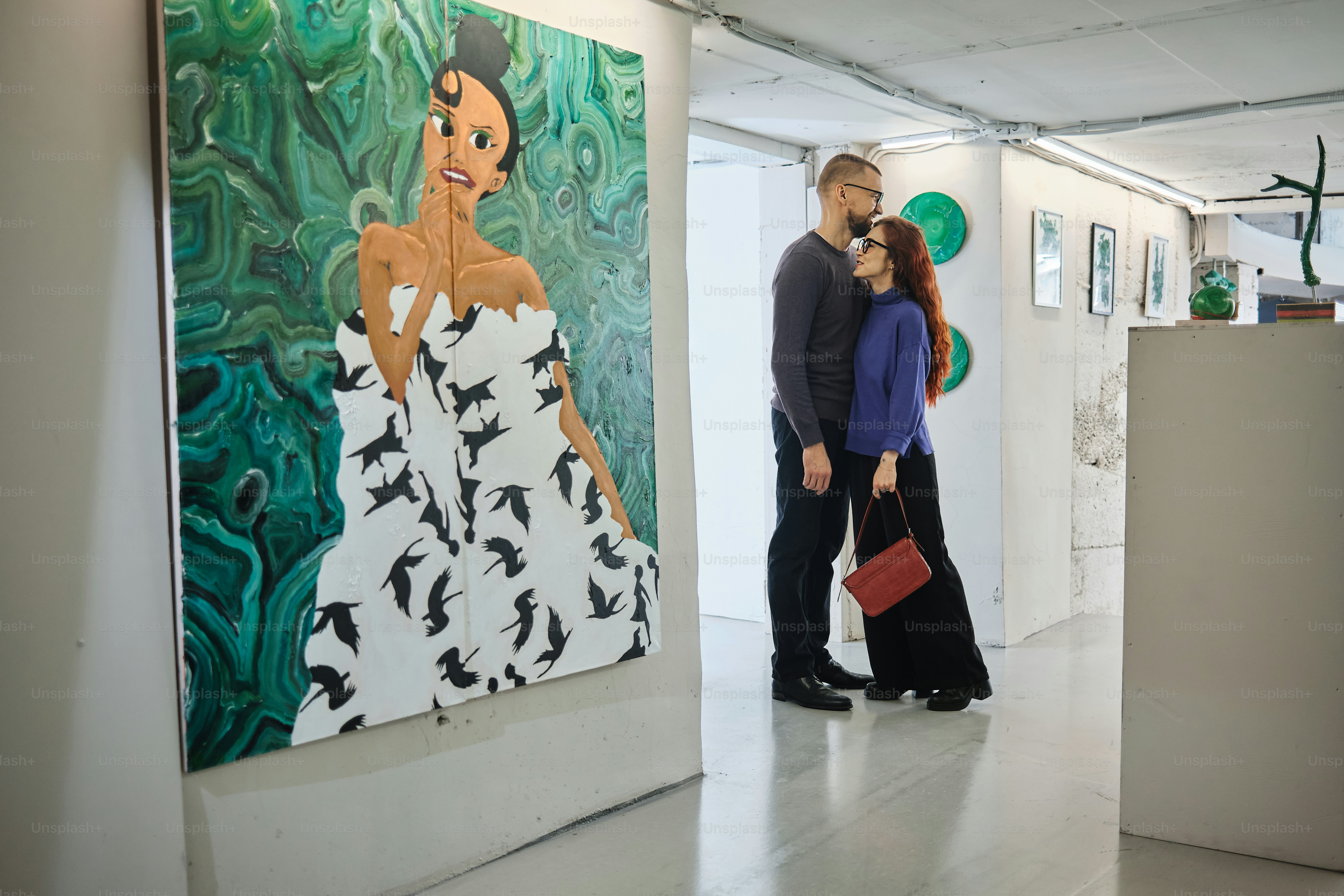 a man and woman standing in front of a painting