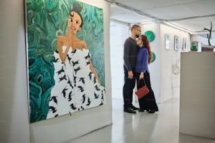a man and woman standing in front of a painting