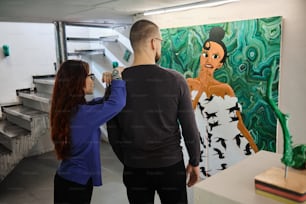 a man and a woman standing in front of a painting