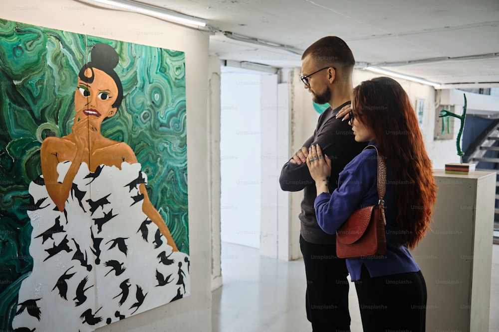 a man and a woman standing in front of a painting