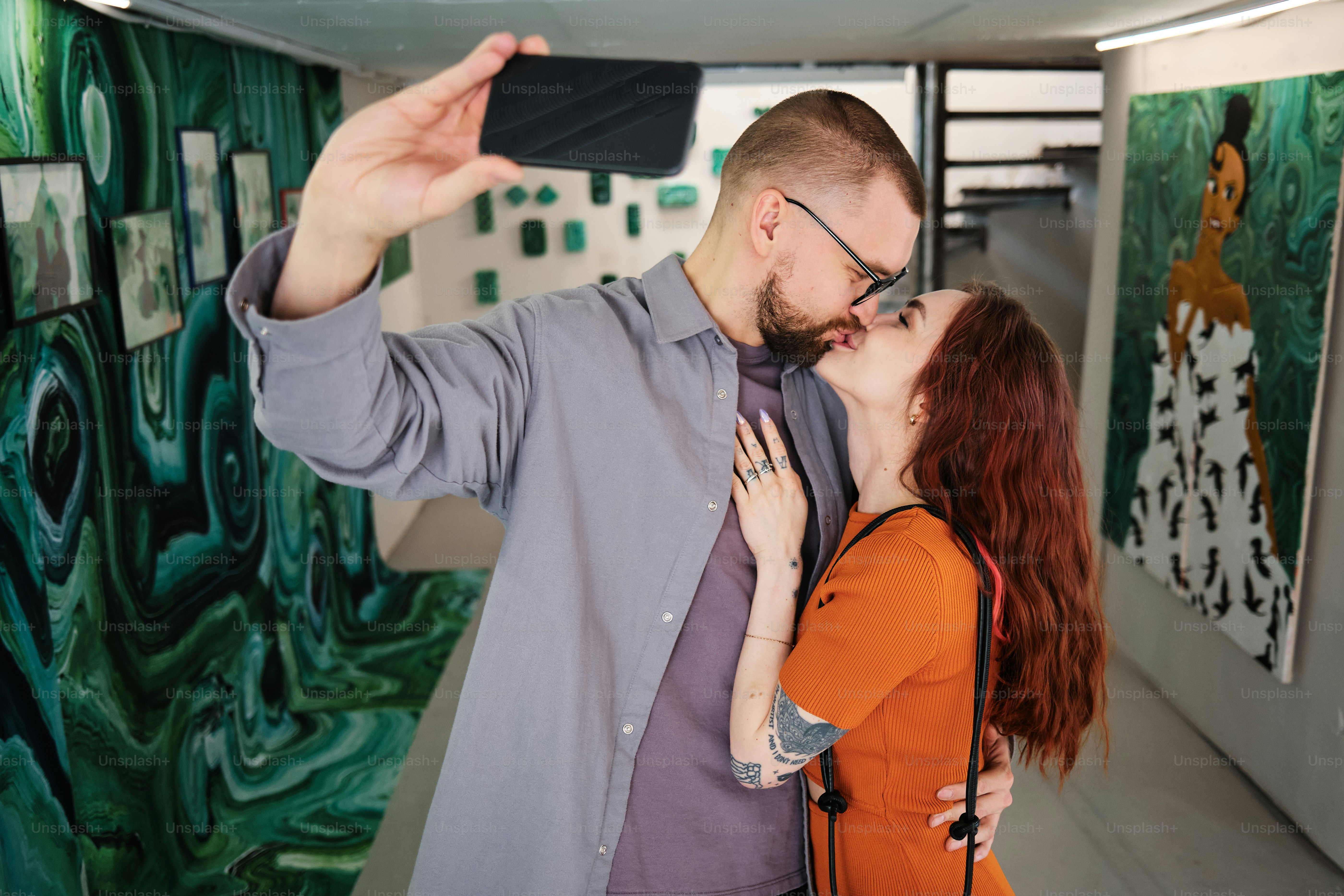 a man taking a picture of a woman kissing him