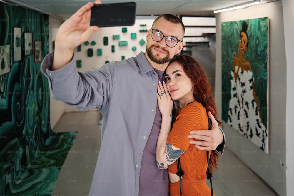 um homem e uma mulher tirando uma selfie com um celular