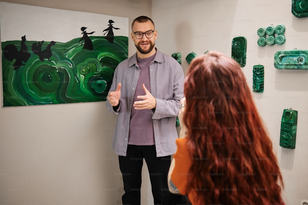 a man standing in front of a painting giving a thumbs up
