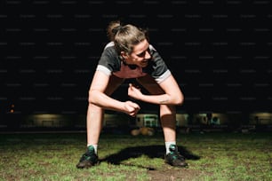 a woman squatting down in a field at night