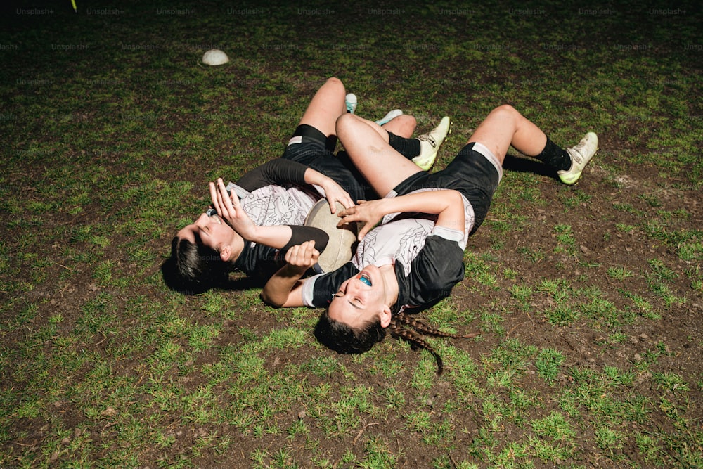 a couple of people laying on top of a lush green field