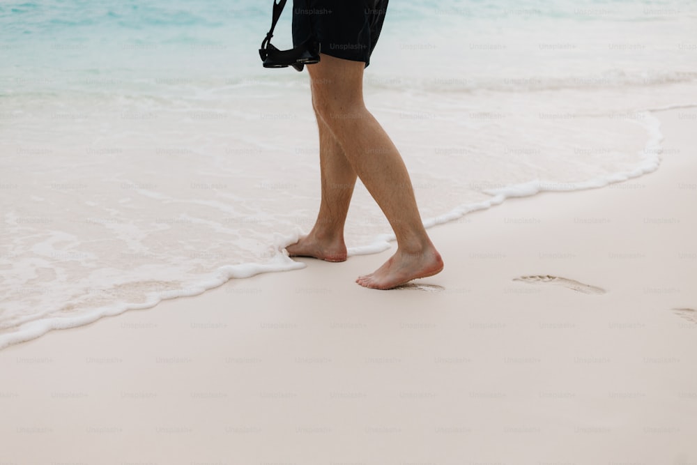 una persona che cammina sulla spiaggia con una macchina fotografica
