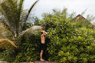 a man standing in front of a lush green bush