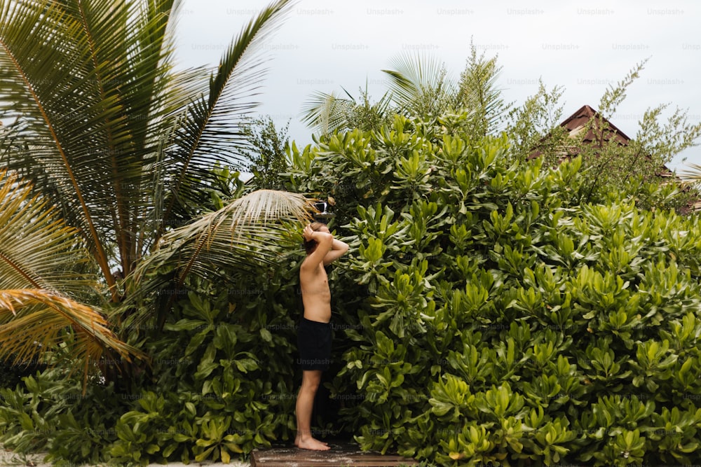 a man standing in front of a lush green bush