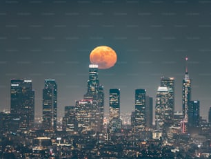 Una luna piena sorge sullo skyline di una città