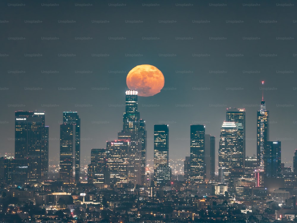 a full moon rises over a city skyline