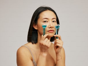 Una mujer sosteniendo dos cepillos de dientes azules frente a su cara