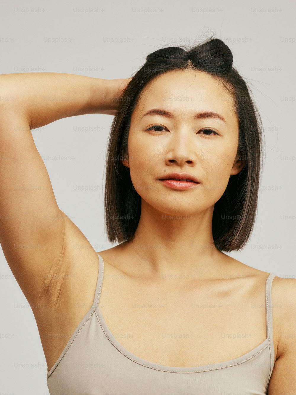 a woman in a tank top holding her hair