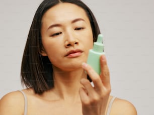 a woman holding a green bottle of lotion in front of her face