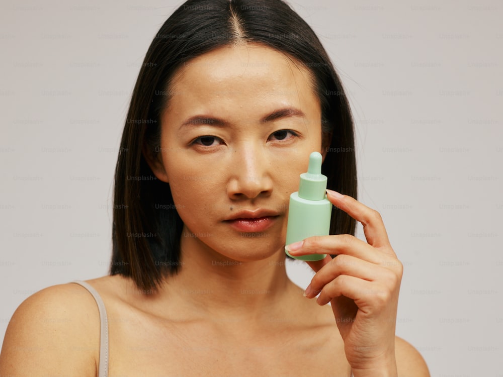 una mujer sosteniendo un frasco de loción frente a su cara