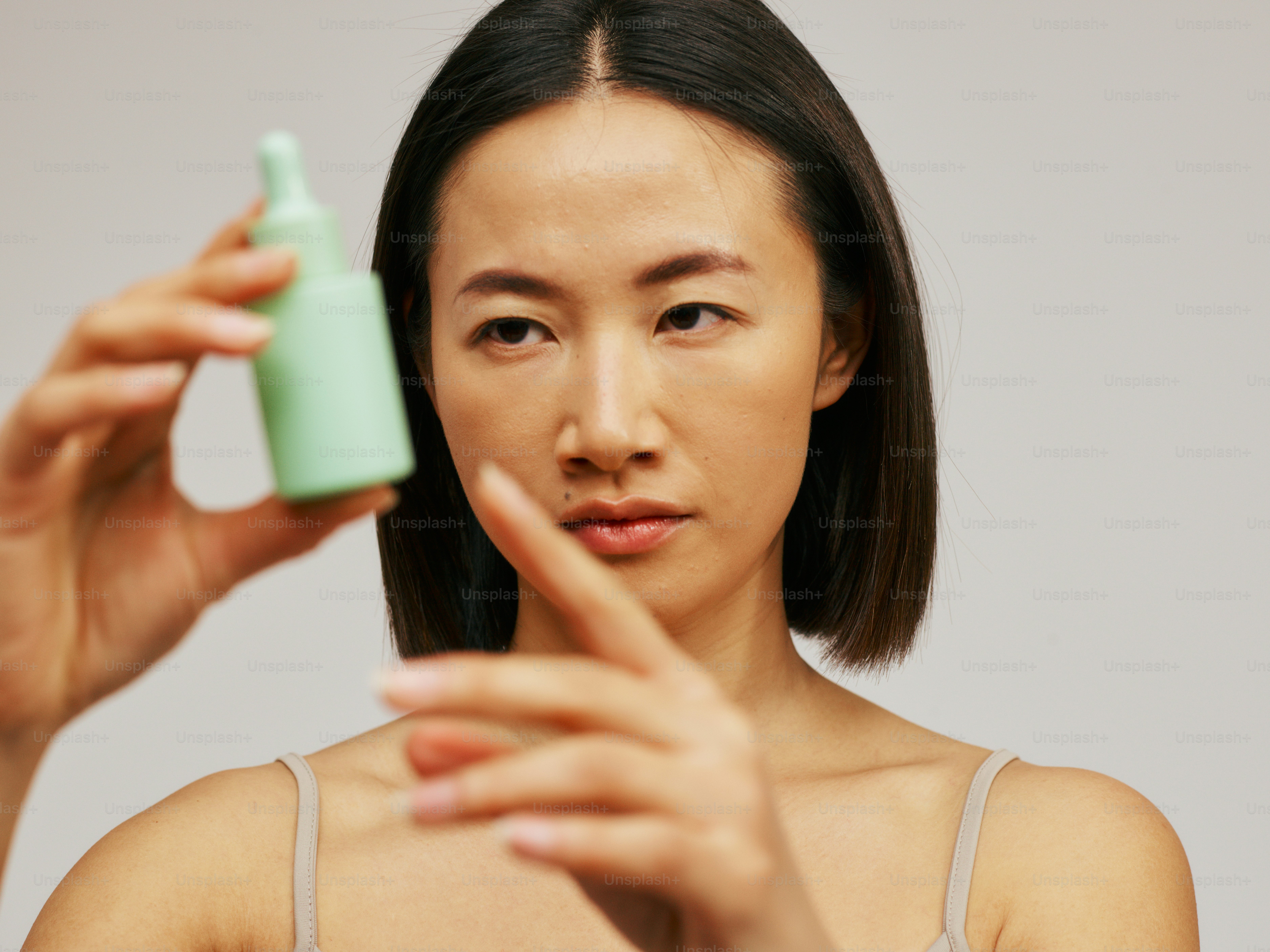 une femme tenant une bouteille de lotion devant son visage