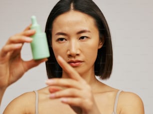 una mujer sosteniendo un frasco de loción frente a su cara