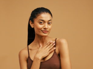 a woman in a brown tank top with her hands on her chest