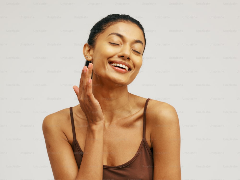 a woman smiling and touching her face with her hands