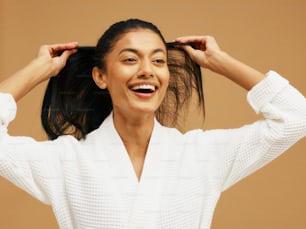 a woman is smiling and holding her hair in her hands