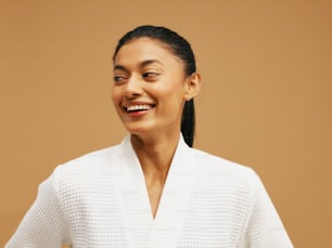 Una donna con un maglione bianco sorride alla telecamera