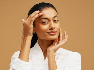 a woman in a bathrobe holding her hand to her face