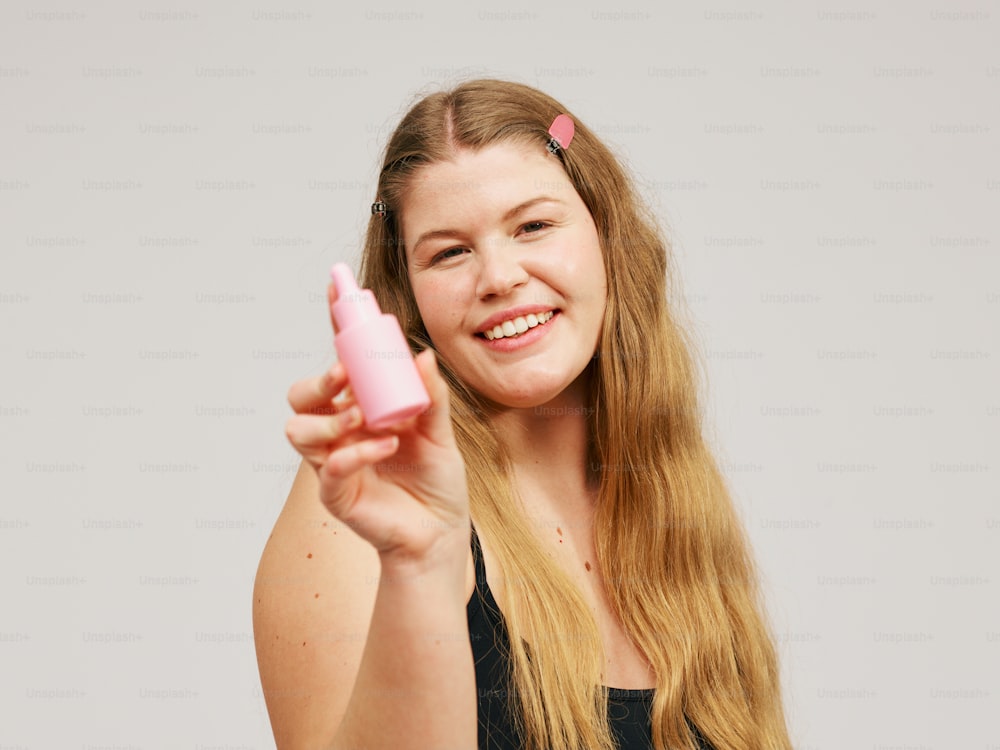 a woman holding a pink object in her right hand