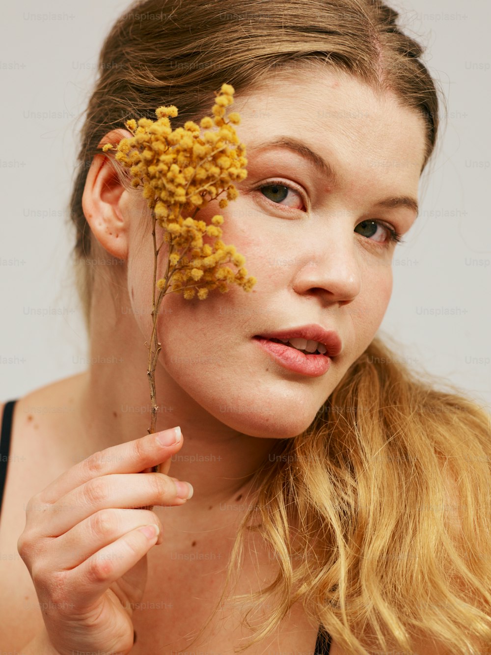 una mujer sosteniendo un ramo de flores frente a su cara