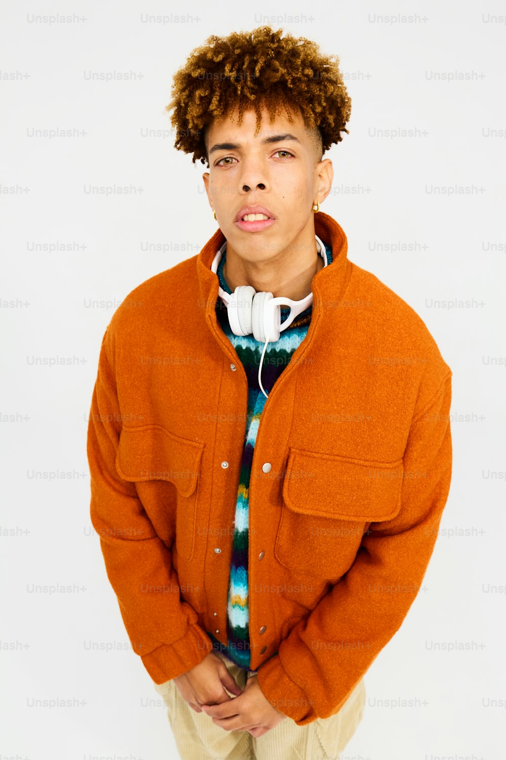 a young man with curly hair wearing an orange jacket