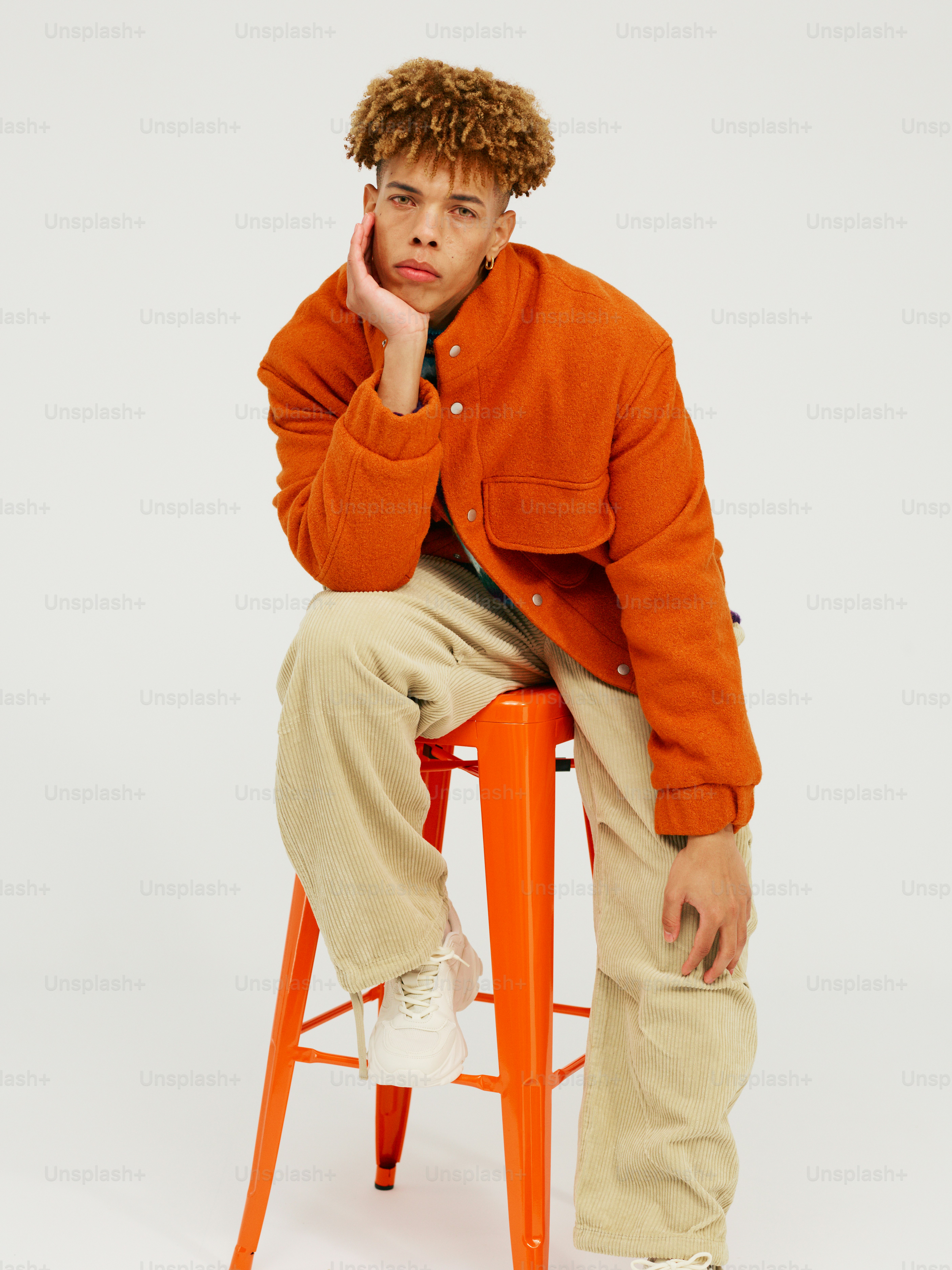 a man sitting on a stool with his hand on his chin