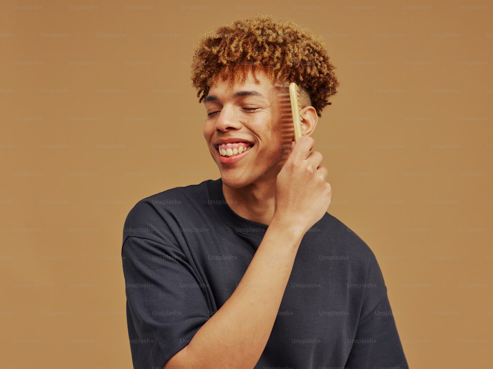 a young man is brushing his hair with a brush