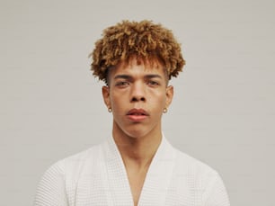 a man with curly hair wearing a white sweater