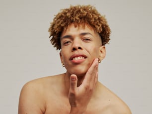 a man with curly hair holding his hand up to his face