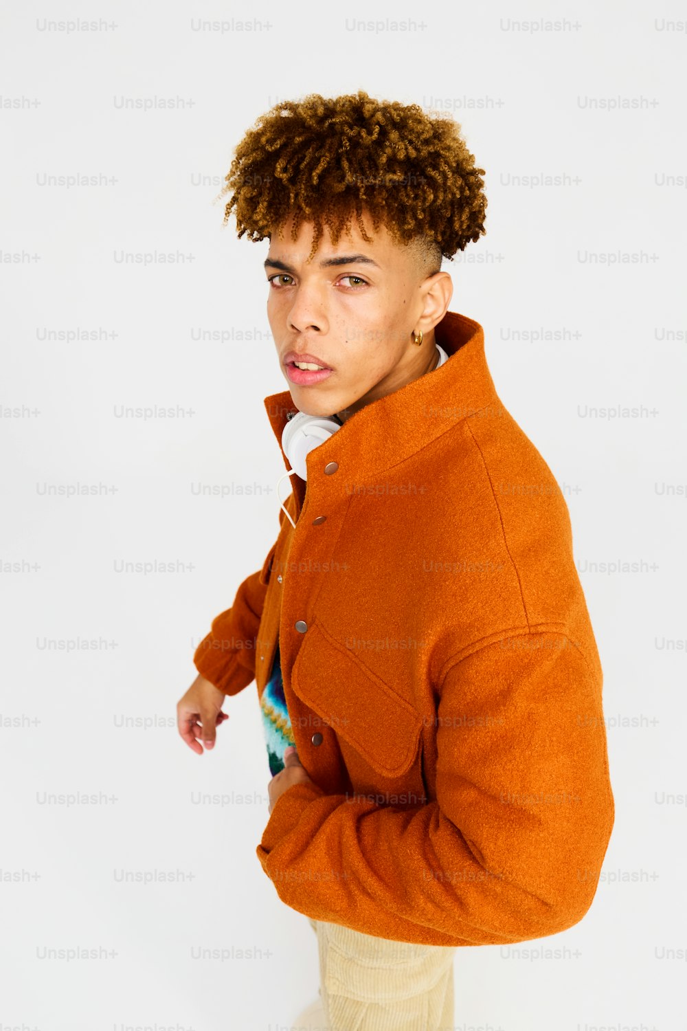um homem com cabelo cacheado usando uma jaqueta laranja