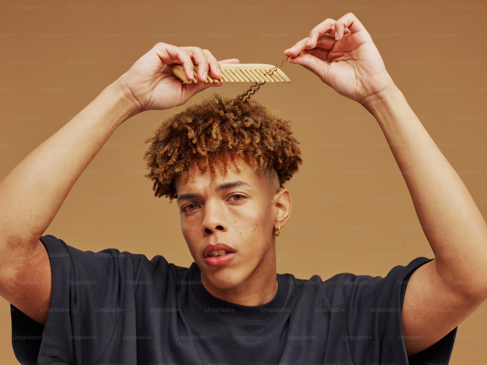 a young man holding a comb over his head