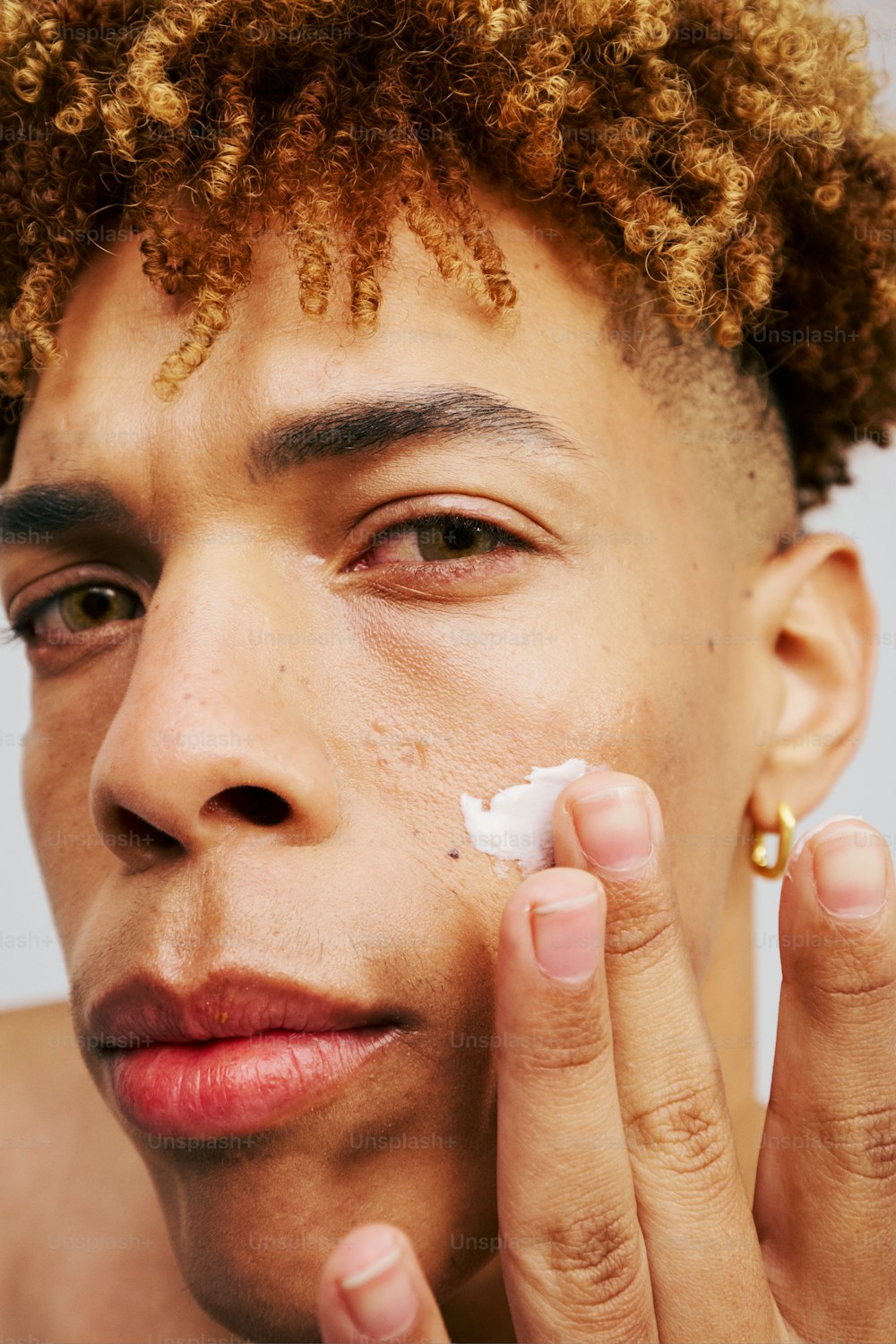 a young man is shaving his face with a cotton pad
