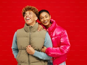 two women standing next to each other in front of a red background