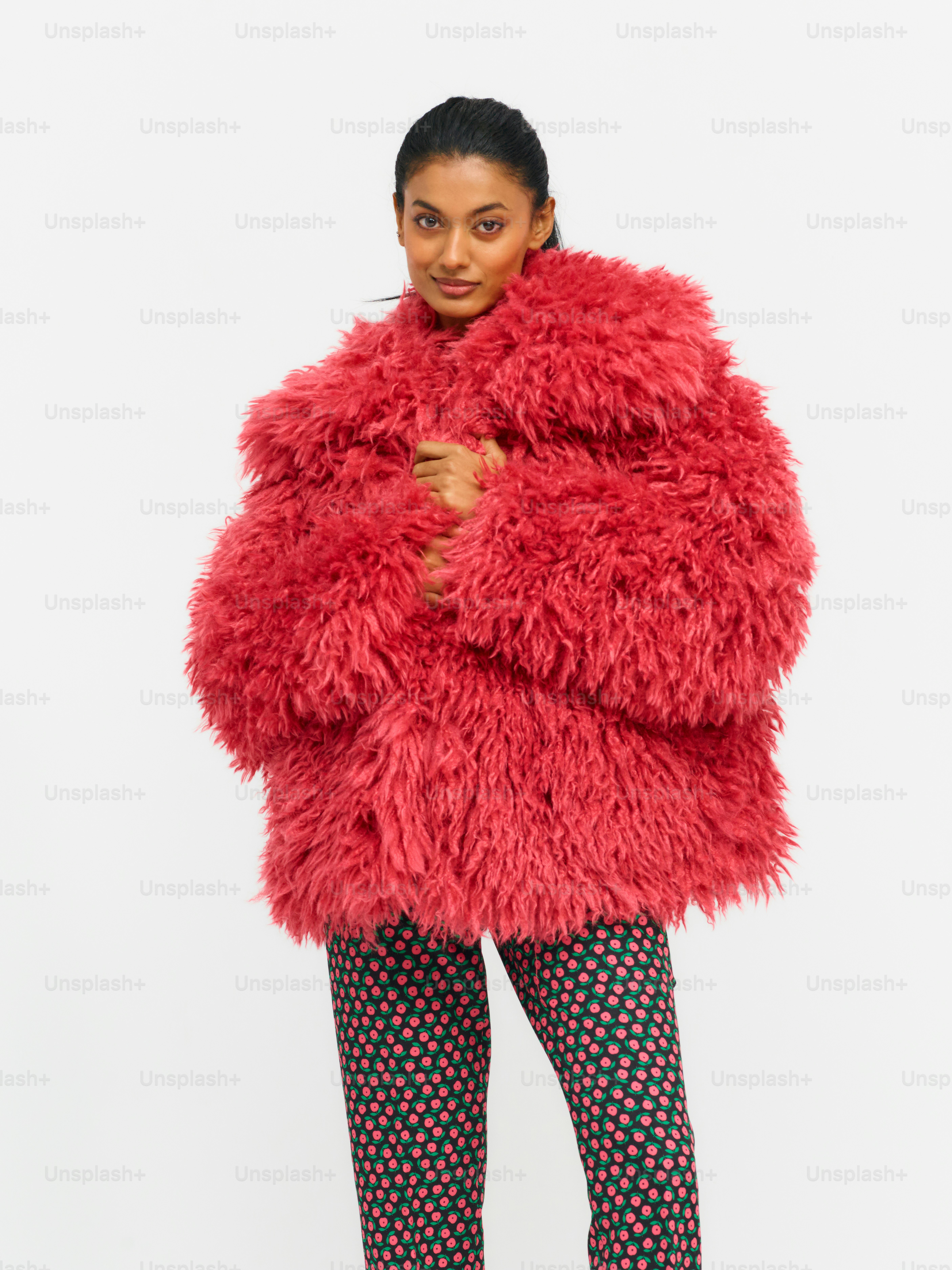 Eine Frau trägt einen roten Mantel und eine gemusterte Hose