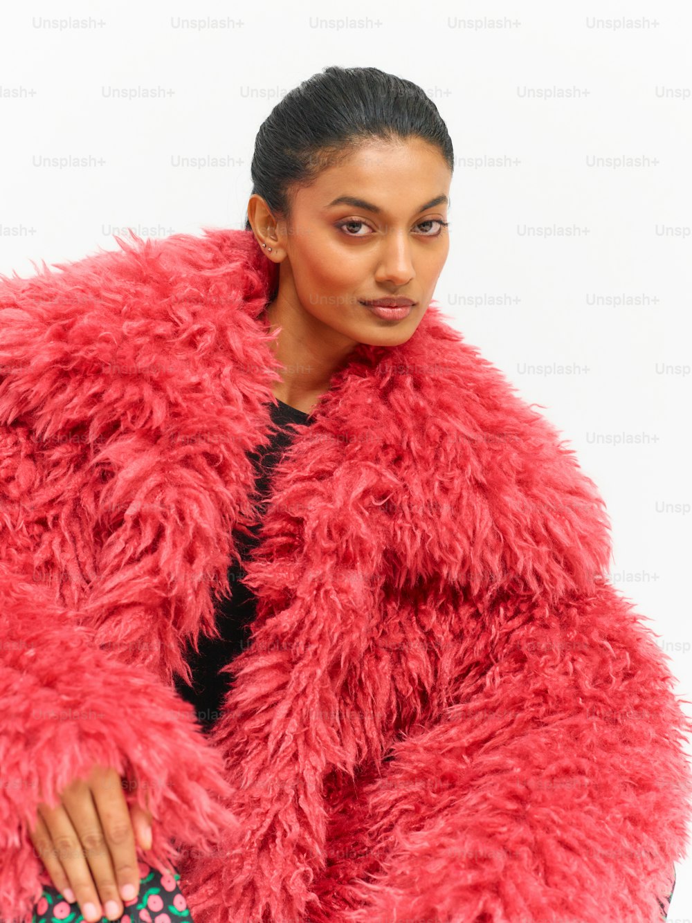 uma mulher em um casaco de pele vermelho posando para uma foto
