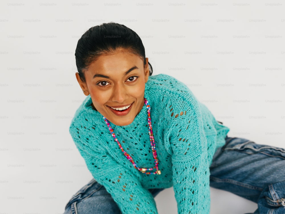 a woman in a blue sweater and jeans posing for a picture