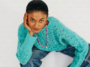 Une femme vêtue d’un pull bleu et d’un jean posant pour une photo