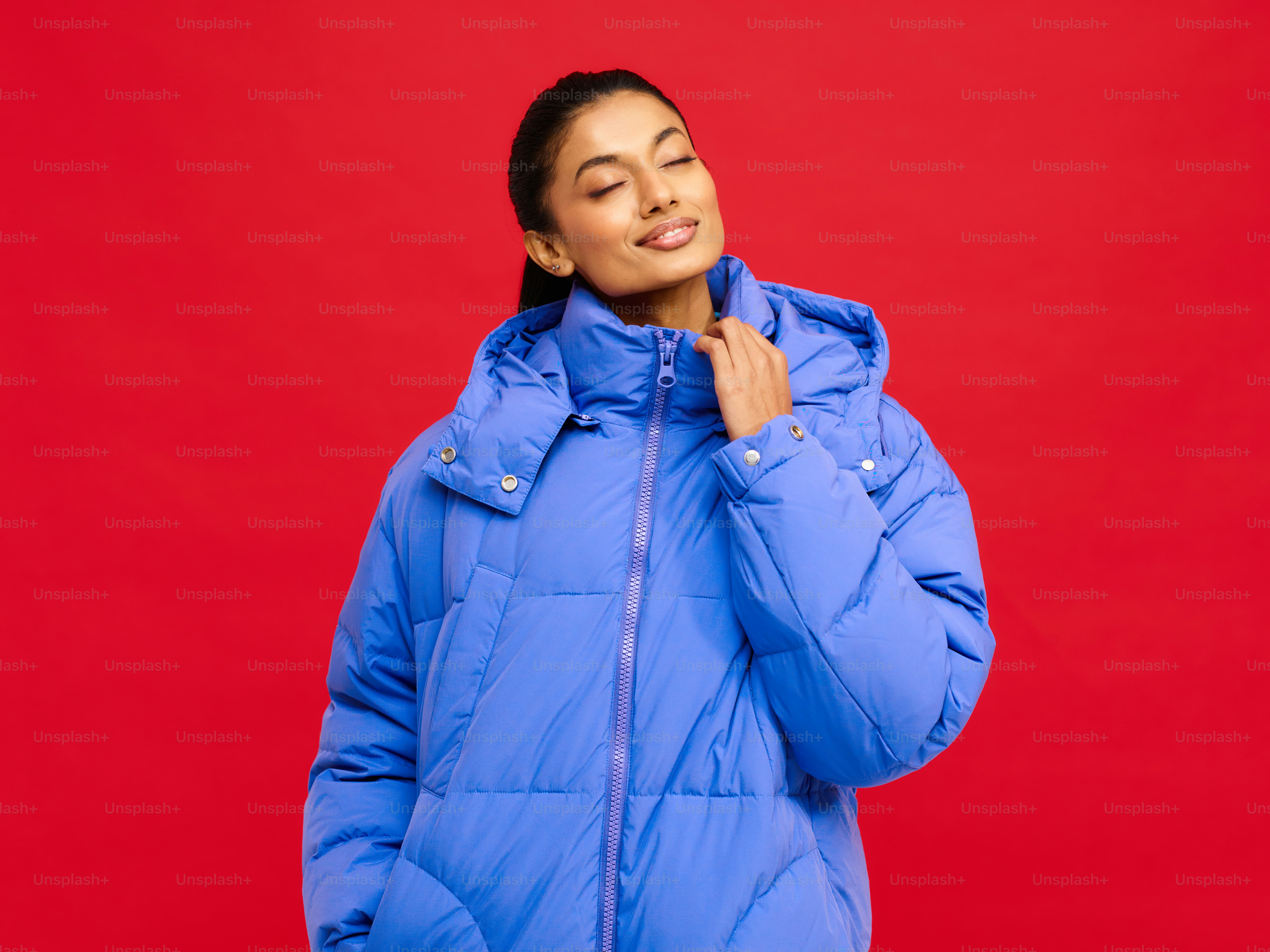eine Frau in einer blauen Jacke, die vor rotem Hintergrund steht