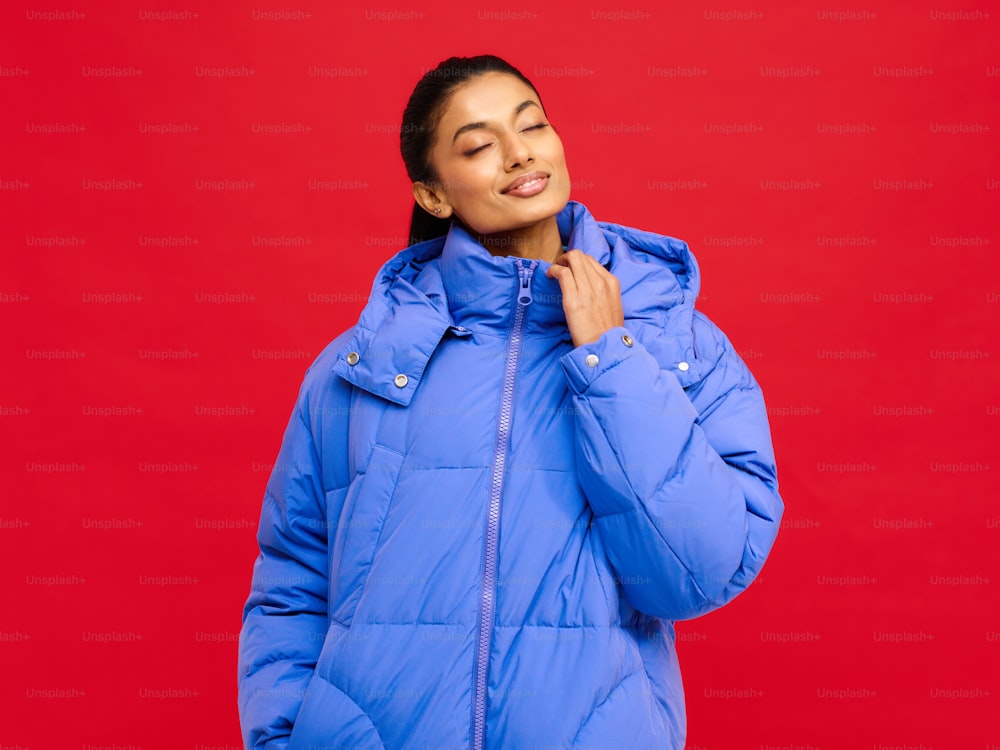 uma mulher em uma jaqueta azul de pé contra um fundo vermelho